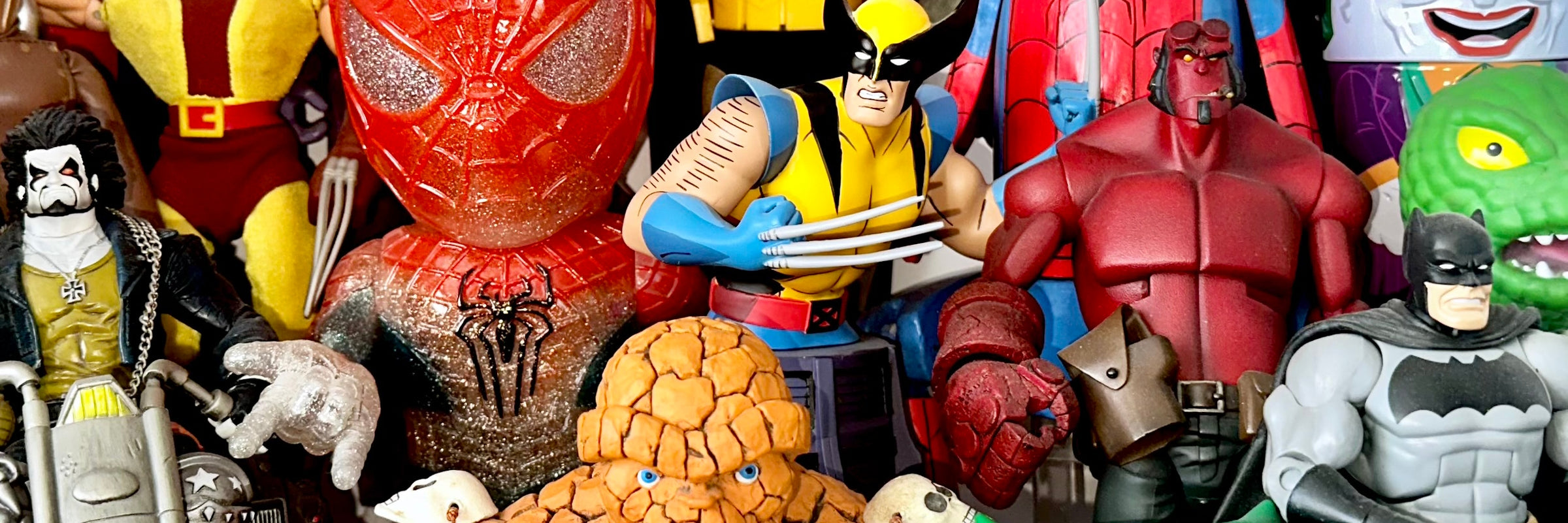 A collection of superhero toys and figures including Batman, Spider-Man, Wolverine, the Thing, Hellboy and the Joker
